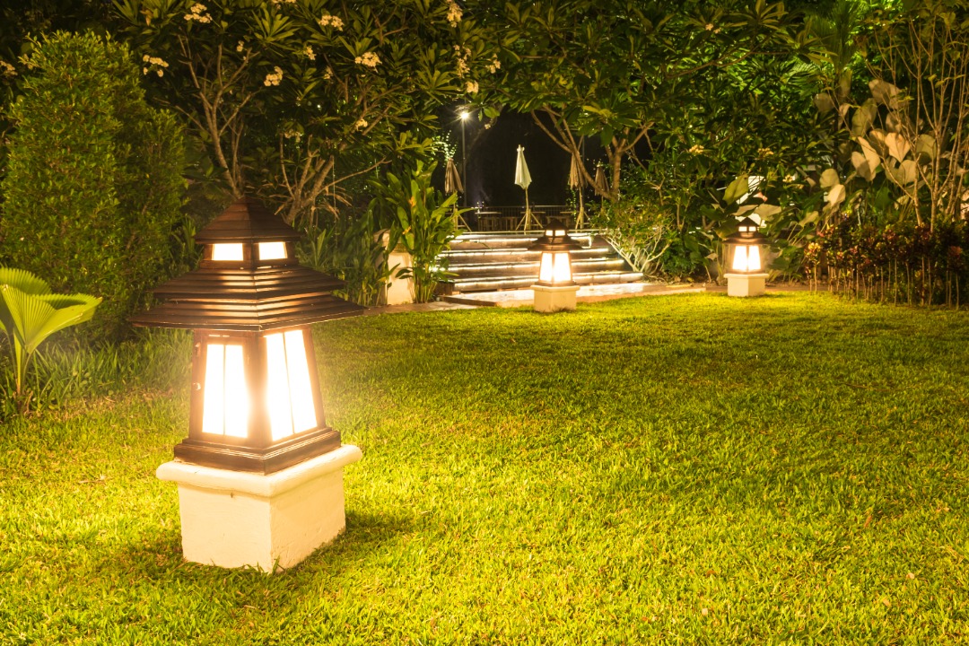 Lantern-style lights illuminate a lush yard, offering inspiration for elegant christmas light installation in garden pathways.