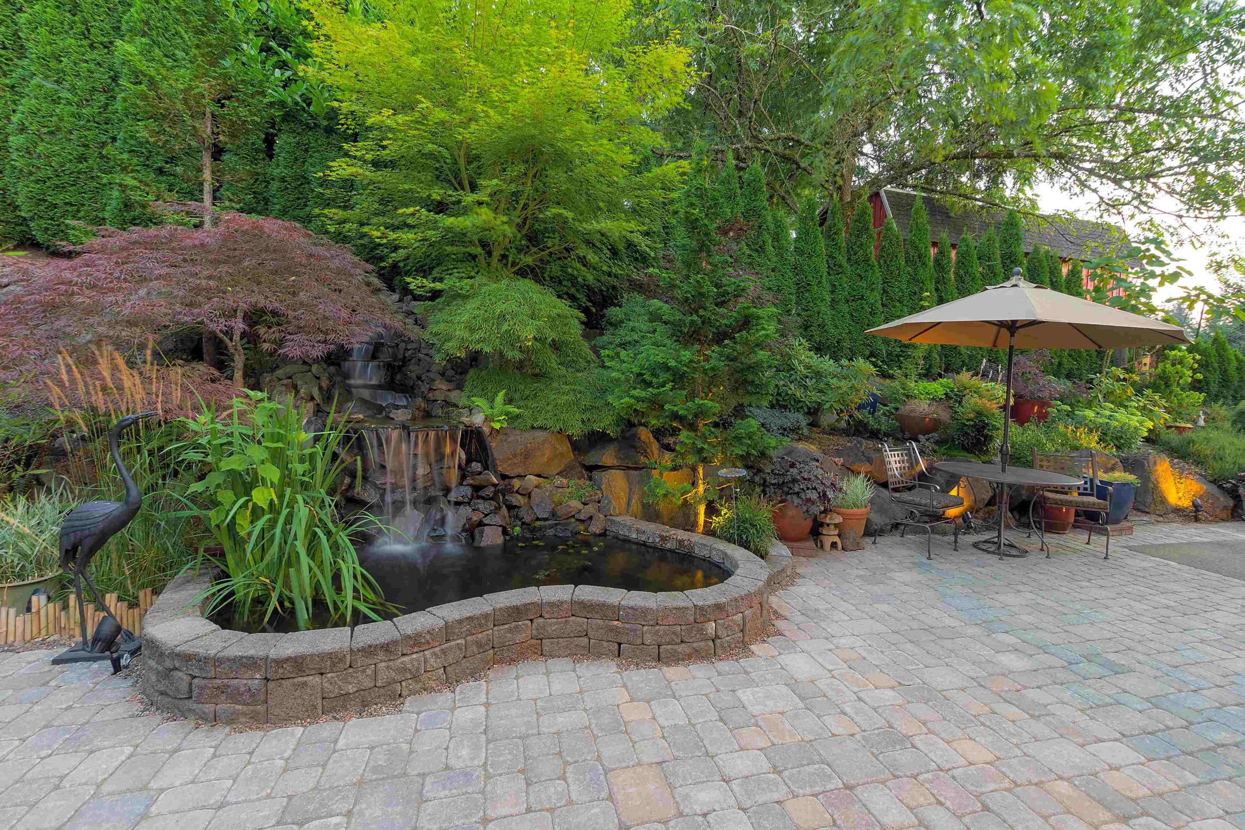 Retaining walls and curved stone steps framing a paver patio edge for stable, slip-resistant access.